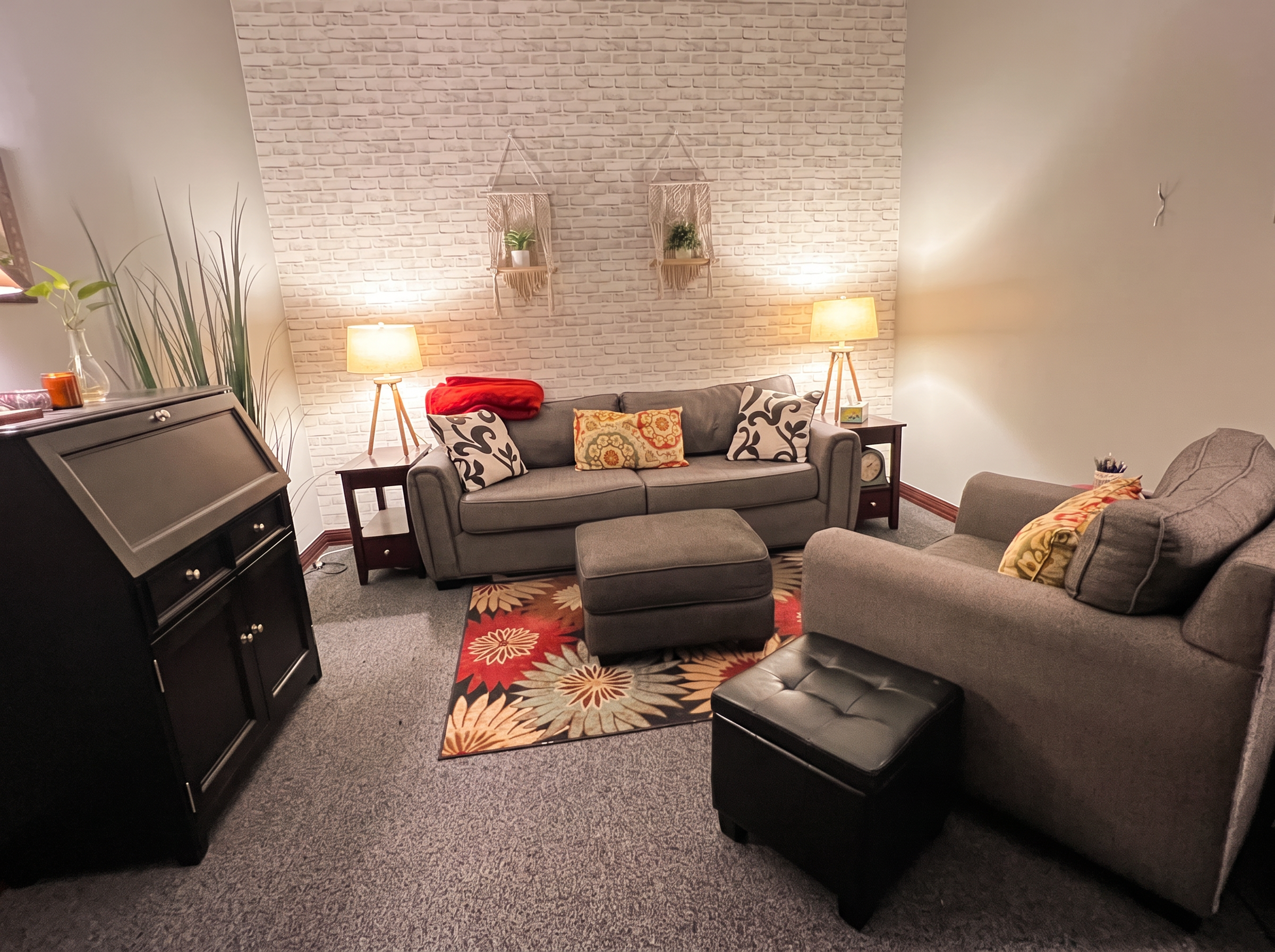 The counseling office: two soft sofas, warm lamplight, and a white brick wall
